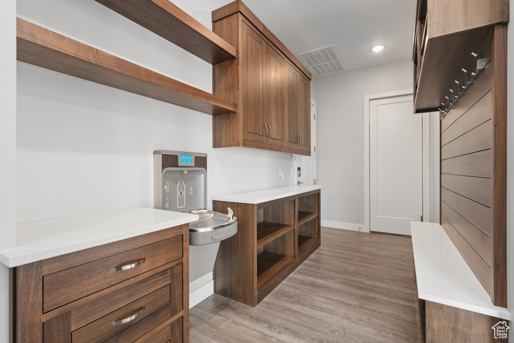 Kitchen featuring open shelves, light wood-style flooring, light countertops, brown cabinets, and recessed lighting