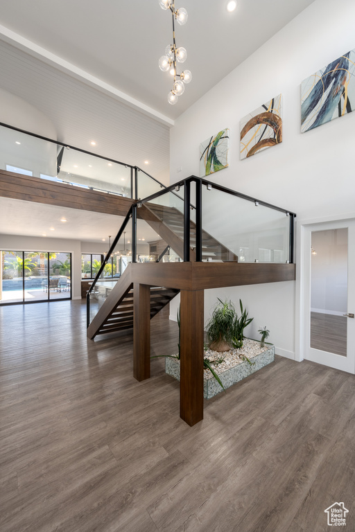 Staircase with wood finished floors, recessed lighting, a chandelier, and a high ceiling