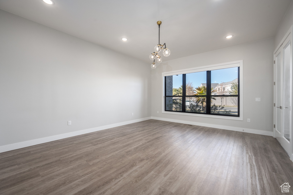 Spare room with a chandelier, wood finished floors, and recessed lighting