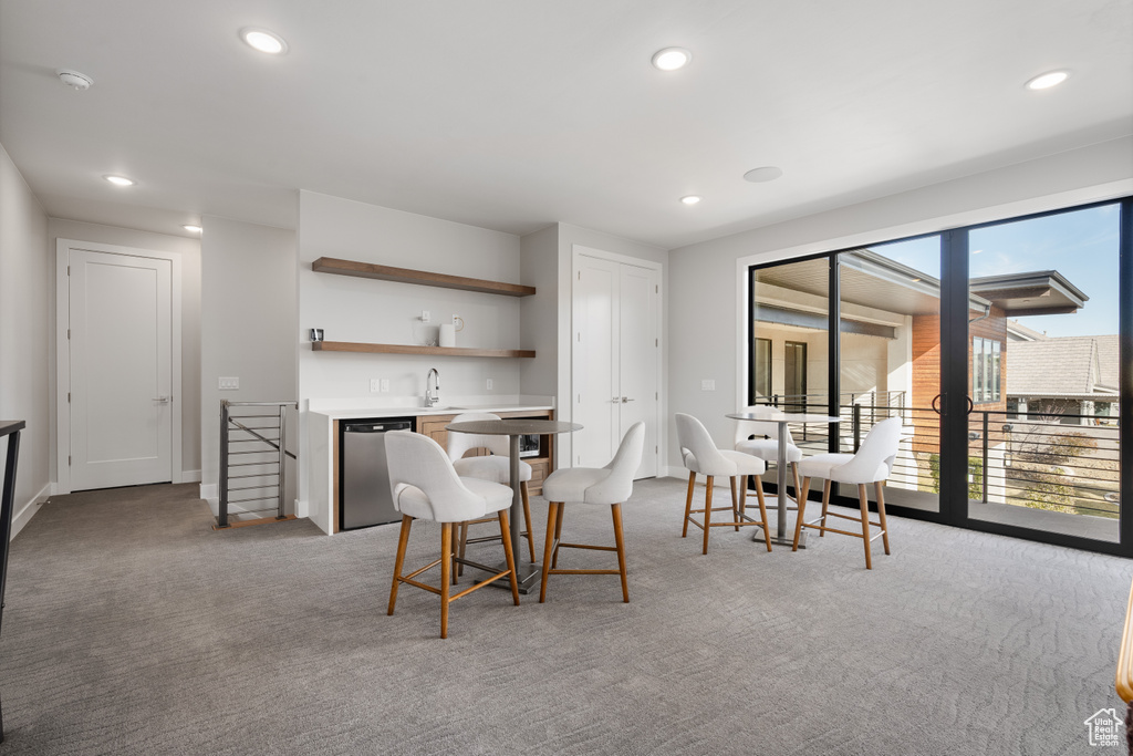 Carpeted dining space with wet bar and recessed lighting