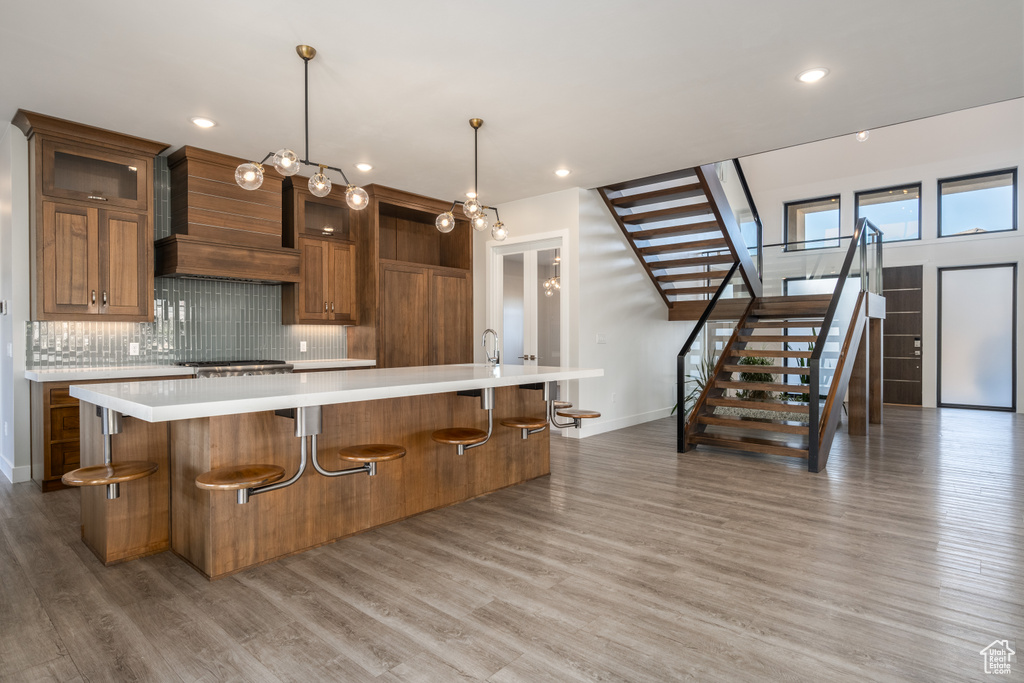 Kitchen featuring light countertops, a large island, tasteful backsplash, brown cabinets, and light wood-style floors