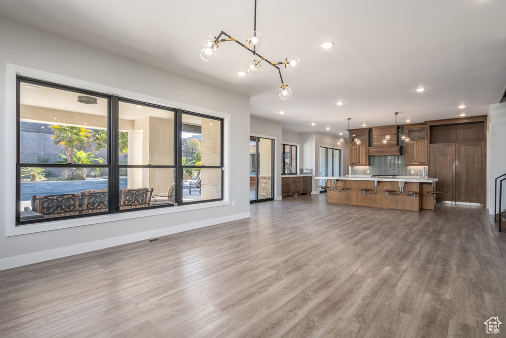 Unfurnished living room with a chandelier, plenty of natural light, recessed lighting, and wood finished floors