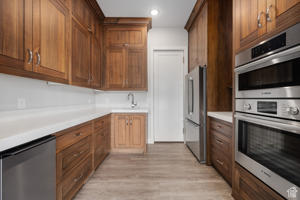 Kitchen with stainless steel appliances, light countertops, light wood-style flooring, and recessed lighting