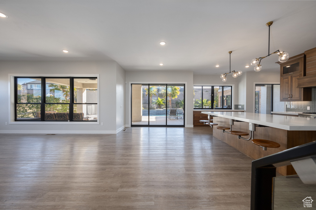 Kitchen featuring light countertops, recessed lighting, wood finished floors, glass insert cabinets, and a kitchen breakfast bar