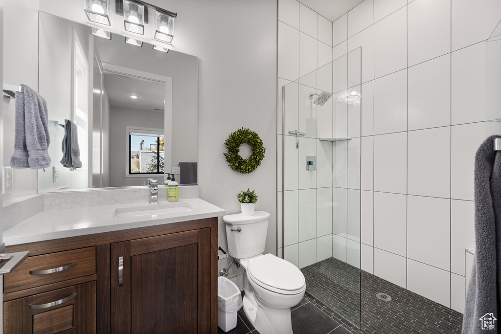 Bathroom with a tile shower, vanity, and tile patterned flooring