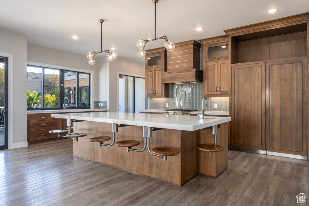 Kitchen with a kitchen island with sink, light countertops, backsplash, dark wood finished floors, and recessed lighting