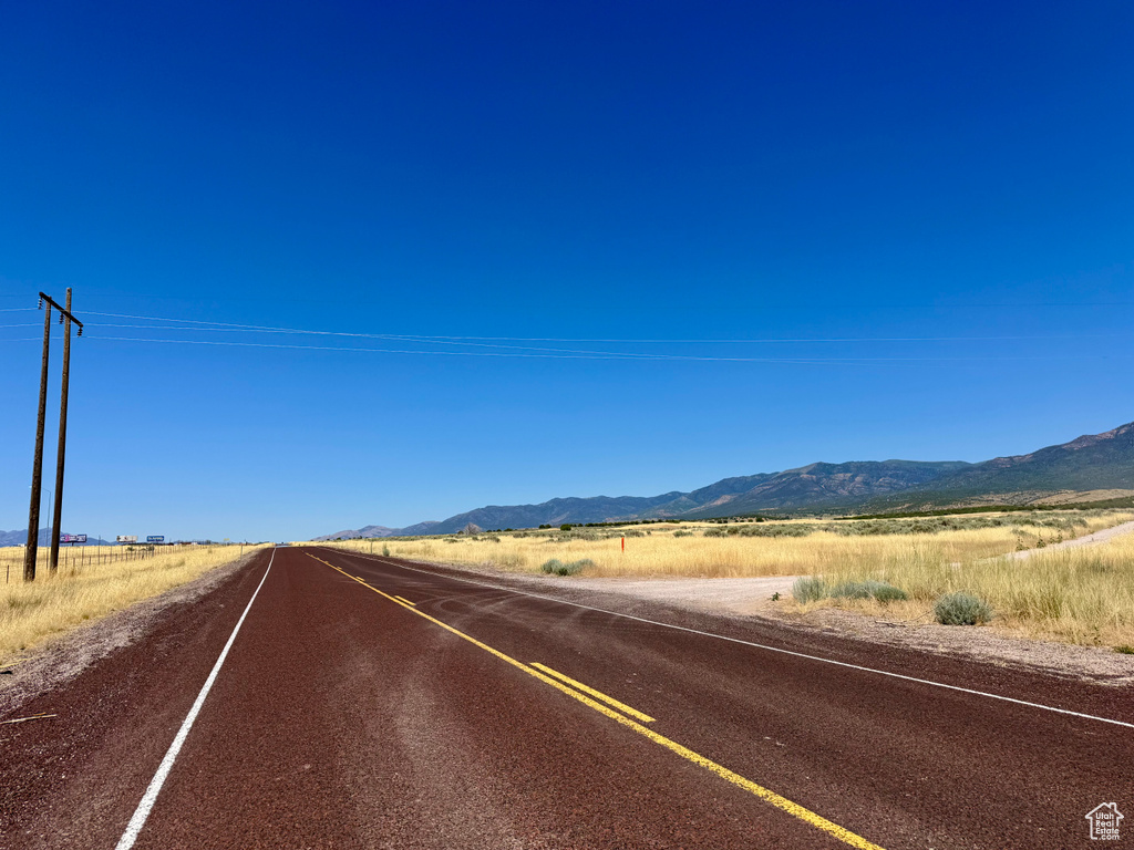 View of asphalt road featuring a mountain view and a rural view