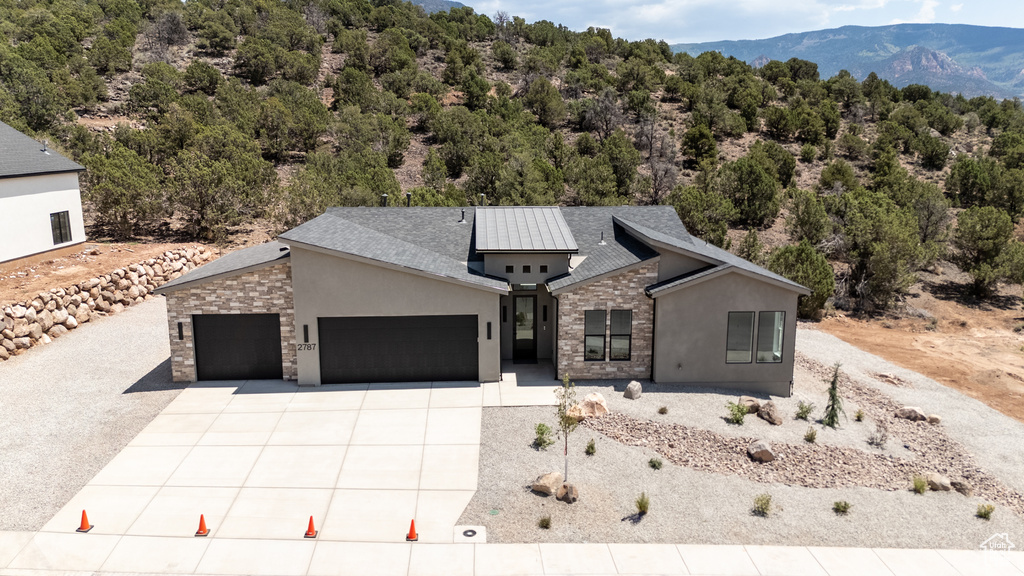 Contemporary home with stone siding, stucco siding, an attached garage, and driveway