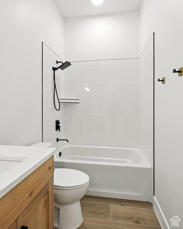 Bathroom with wood finished floors, vanity, and shower / tub combination