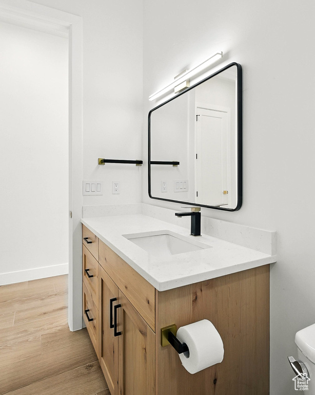 Half bathroom featuring vanity and wood finished floors