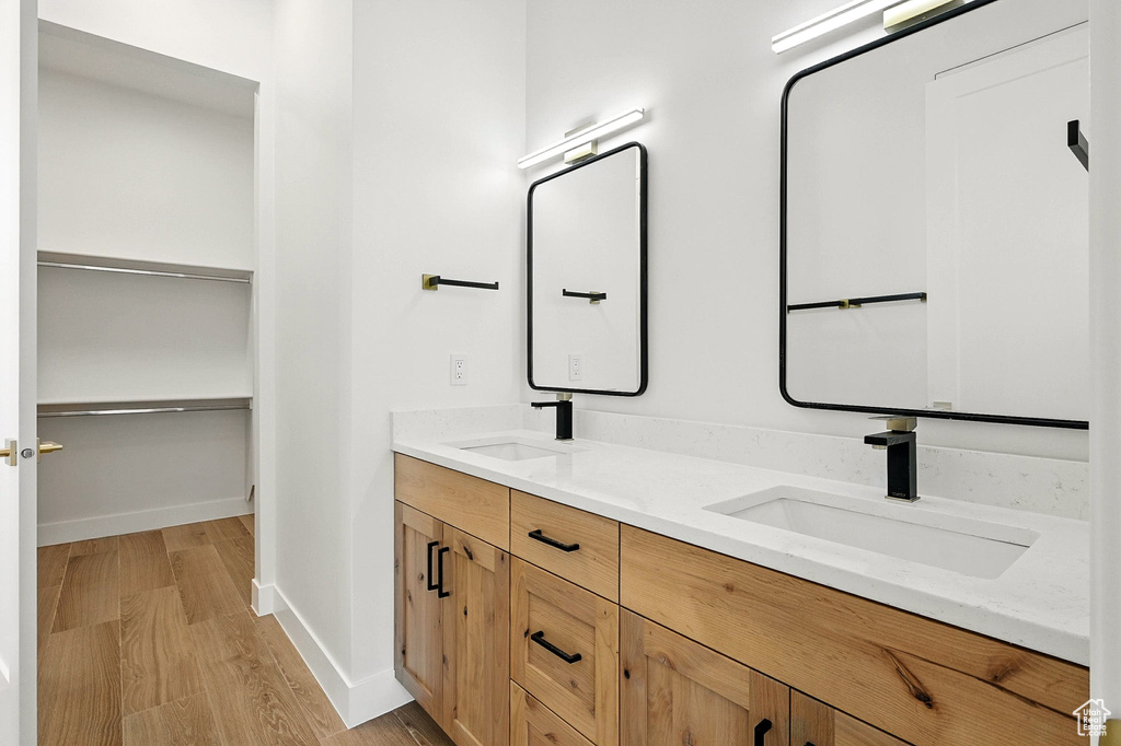 Bathroom with wood finished floors, double vanity, and a spacious closet
