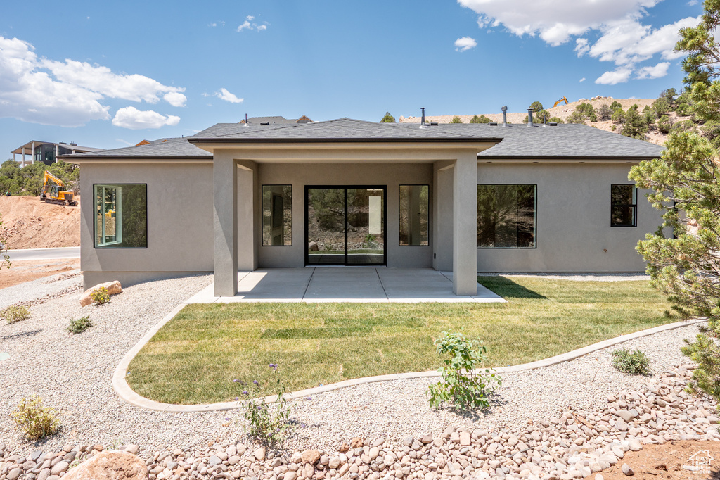Rear view of house with stucco siding, a patio, and a yard