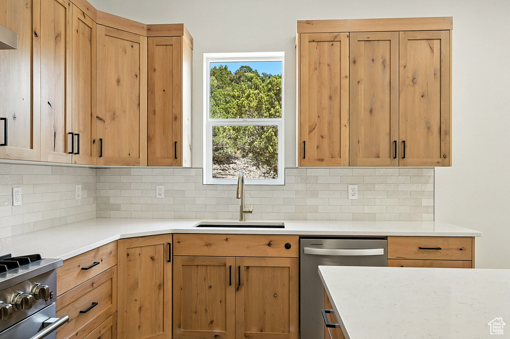 Kitchen with appliances with stainless steel finishes, decorative backsplash, and light countertops