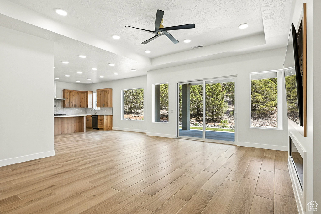 Unfurnished living room featuring light wood finished floors, recessed lighting, a ceiling fan, and a textured ceiling