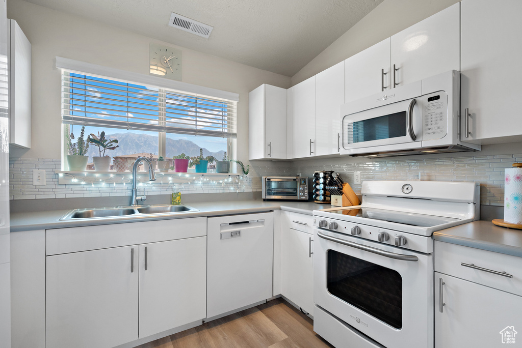 Kitchen with white appliances, decorative backsplash, and light countertops
