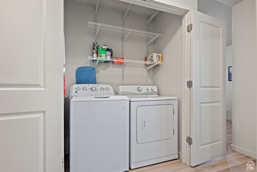 Laundry room with washer and dryer and light wood finished floors