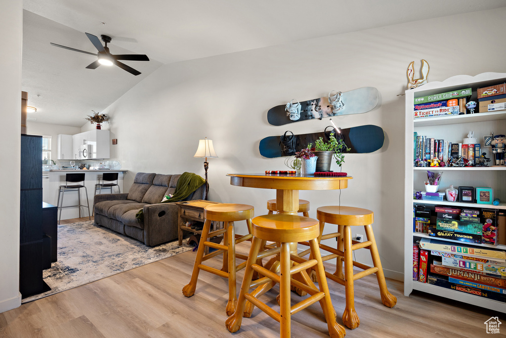 Dining space with ceiling fan, wood finished floors, and lofted ceiling