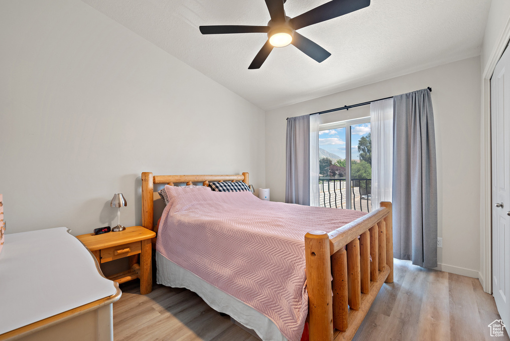 Bedroom featuring light wood-type flooring, vaulted ceiling, access to exterior, and a ceiling fan