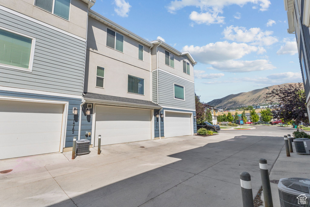 View of property exterior with a mountain view, an attached garage, driveway, and stucco siding
