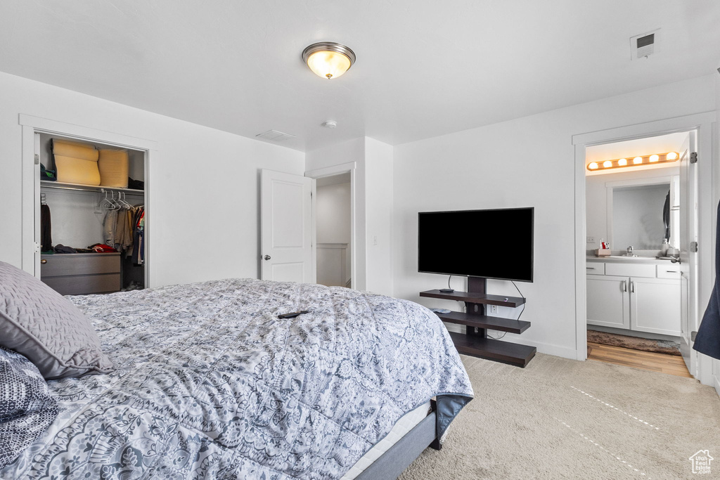 Bedroom featuring ensuite bathroom, a spacious closet, and light carpet