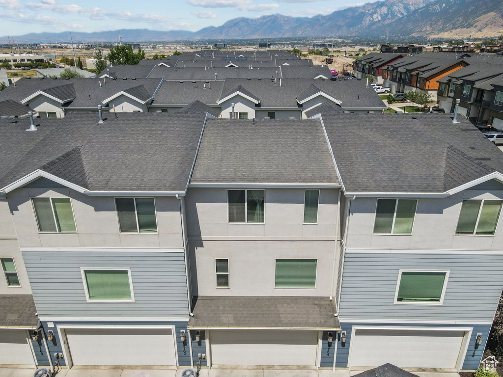 View of front of home with a garage, a mountain view, a shingled roof, and a residential view