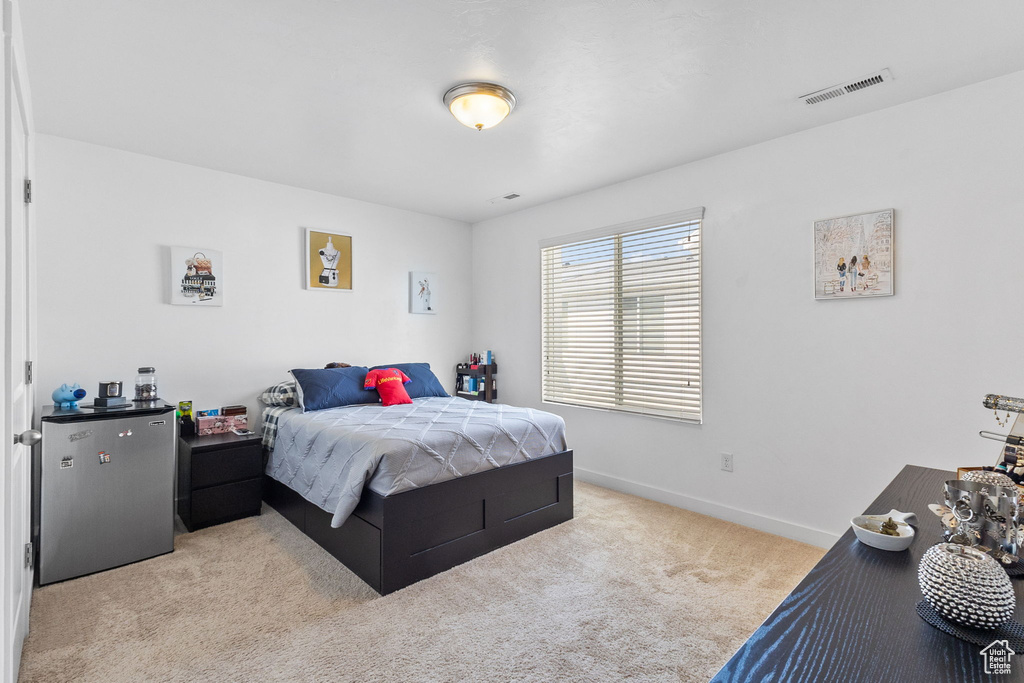 Bedroom with freestanding refrigerator and carpet floors