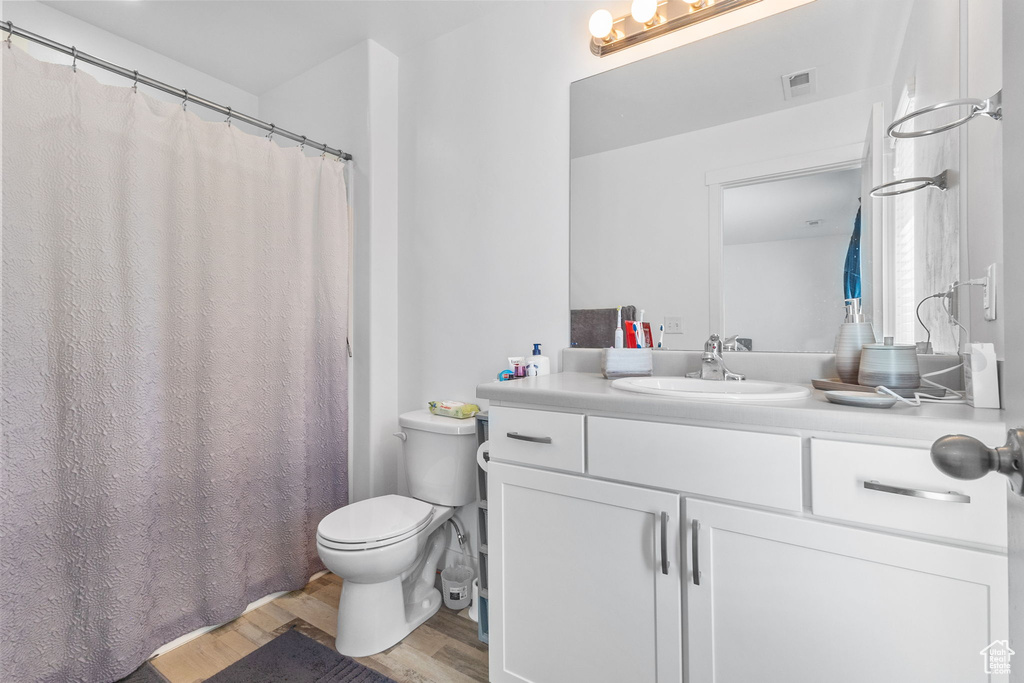 Full bath with wood finished floors, vanity, and curtained shower