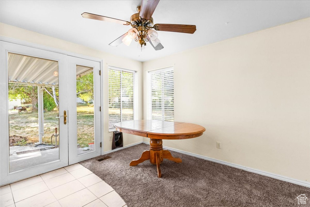 Dining area featuring light colored carpet, ceiling fan, and light tile patterned floors
