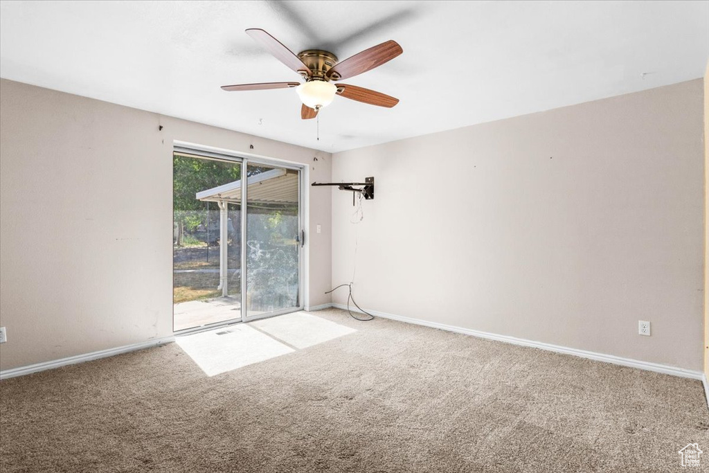 Carpeted spare room with ceiling fan and baseboards