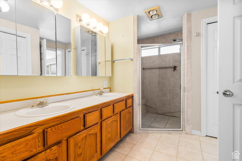 Bathroom featuring double vanity, a stall shower, tile patterned floors, and a closet