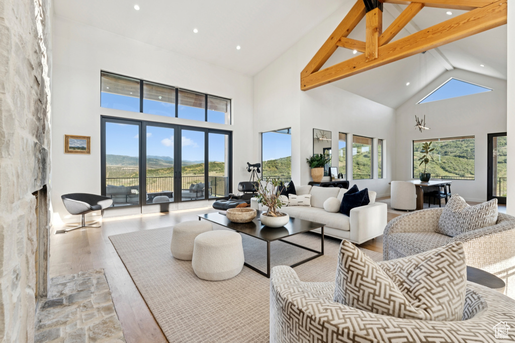 Living room featuring high vaulted ceiling, wood finished floors, a fireplace, recessed lighting, and beamed ceiling