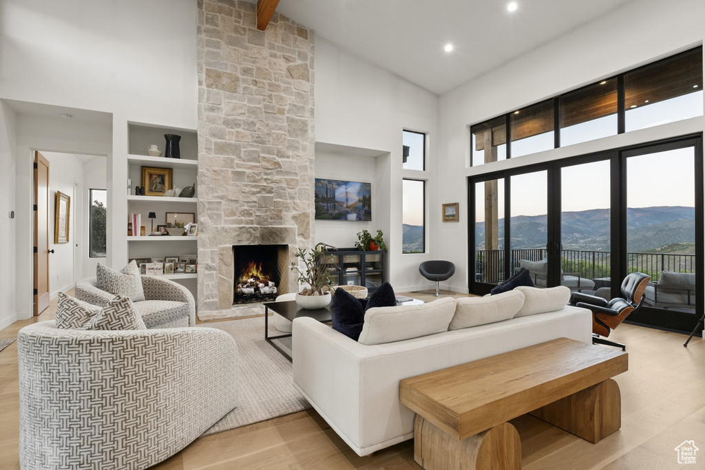 Living area with high vaulted ceiling, a mountain view, a fireplace, built in features, and wood finished floors