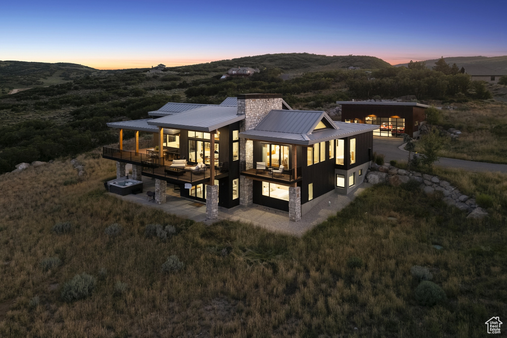 Rear view of house with a metal roof, a standing seam roof, a mountain view, a chimney, and stone siding
