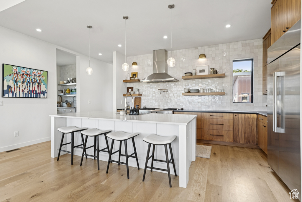 Kitchen with open shelves, brown cabinetry, built in fridge, light wood-style flooring, and recessed lighting