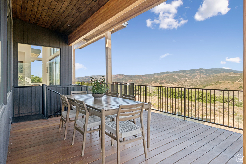 Wooden terrace featuring a mountain view and outdoor dining space