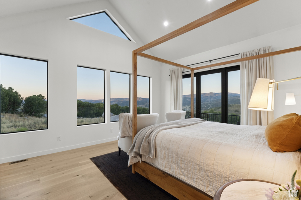 Bedroom featuring wood finished floors, high vaulted ceiling, multiple windows, and a mountain view