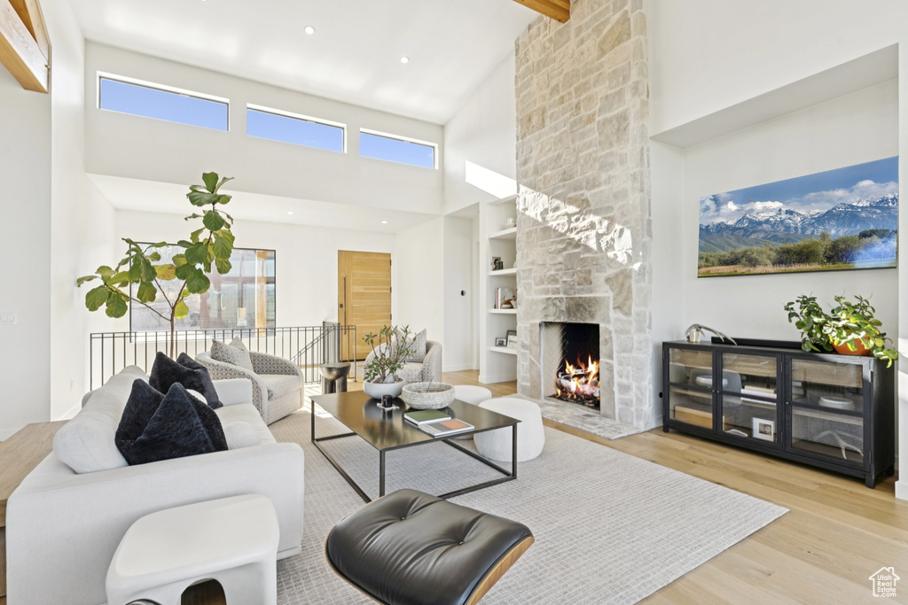 Living area featuring a high ceiling, wood finished floors, a fireplace, and beam ceiling