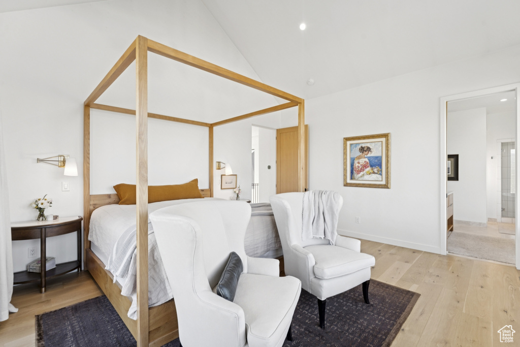 Bedroom with light wood-style flooring, ensuite bath, recessed lighting, and lofted ceiling