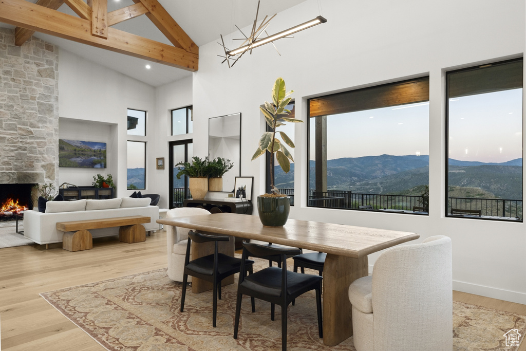Dining area with high vaulted ceiling, a mountain view, wood finished floors, beamed ceiling, and healthy amount of natural light