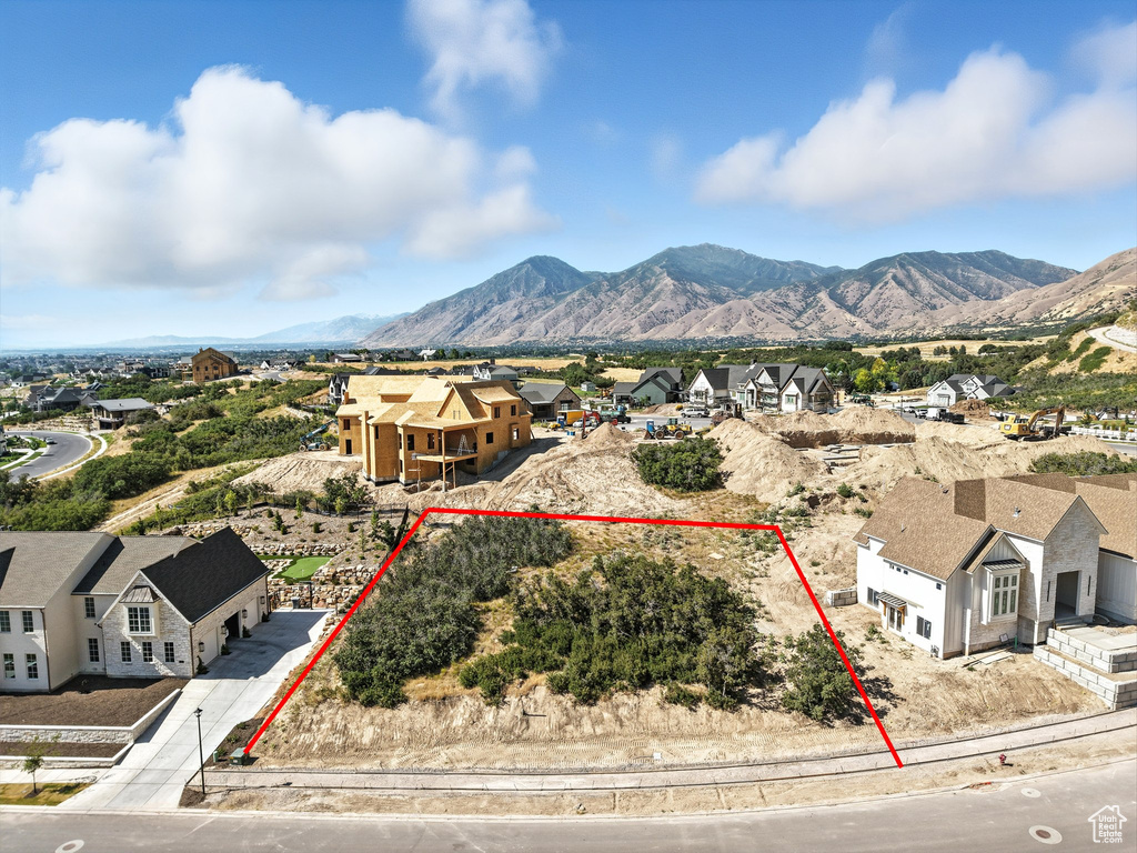 Aerial view of residential area featuring property boundaries highlighted and a mountain backdrop