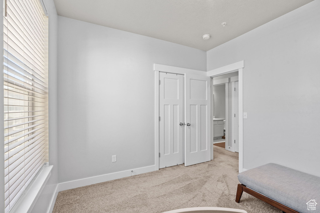 Bedroom with light colored carpet and a closet