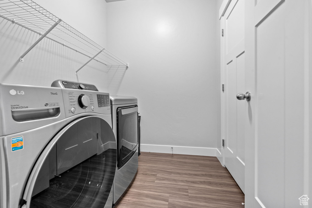 Laundry room with washing machine and dryer and wood finished floors