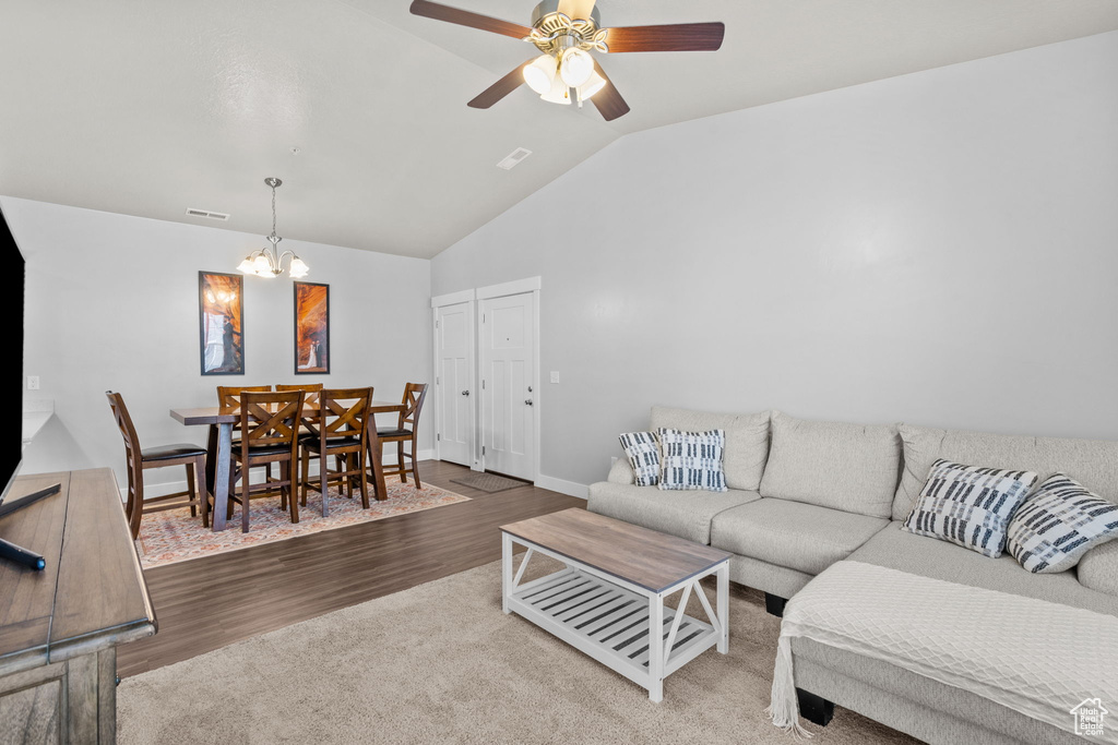 Living area with a chandelier, vaulted ceiling, wood finished floors, and ceiling fan