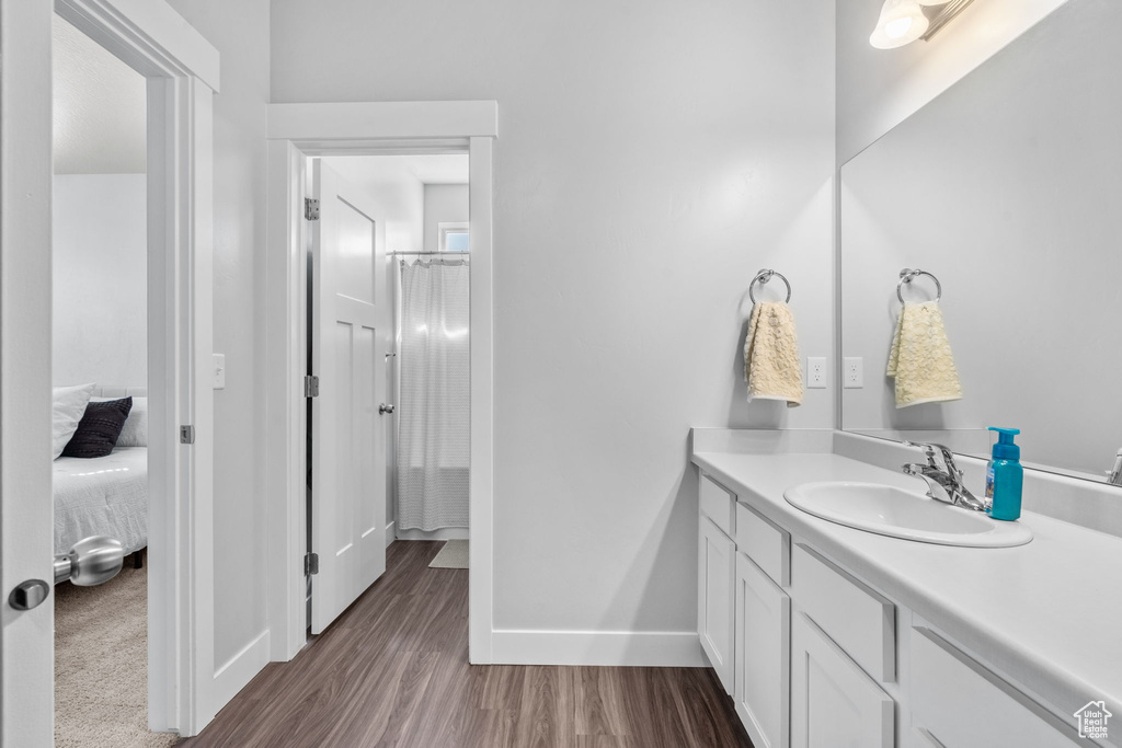 Ensuite bathroom featuring vanity, wood finished floors, and a shower with shower curtain