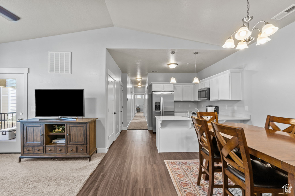 Dining area with vaulted ceiling, a chandelier, and wood finished floors