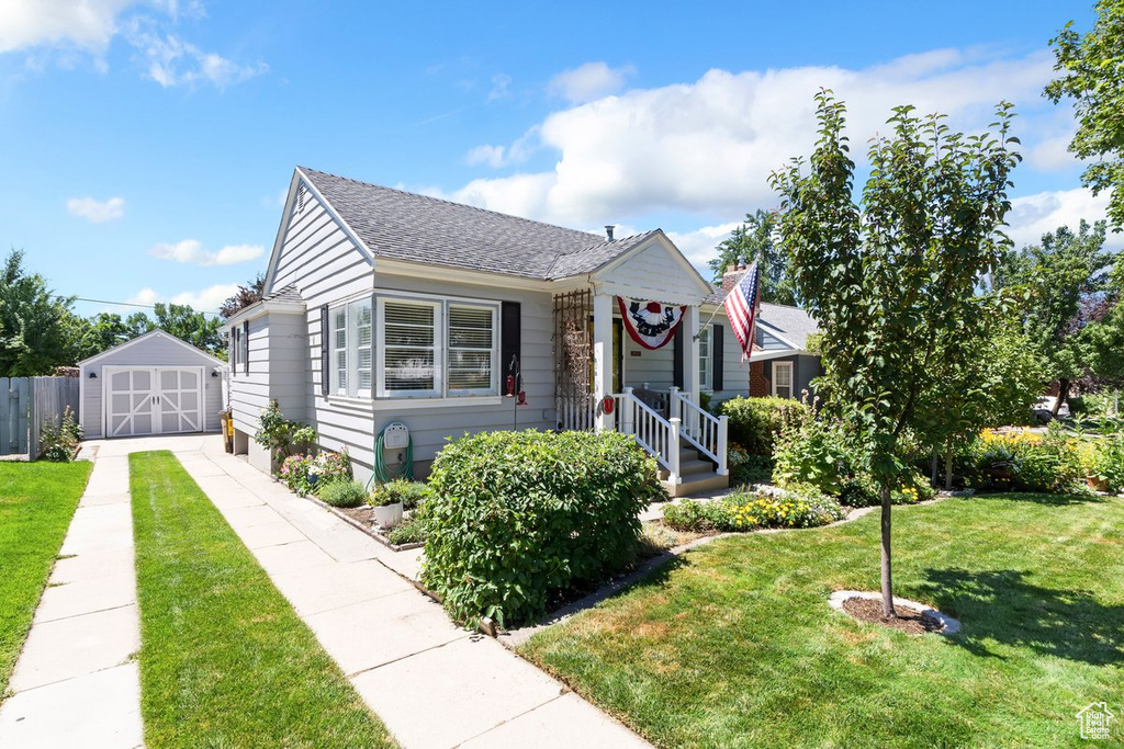 Bungalow-style house with a detached garage, a shed, roof with shingles, and driveway