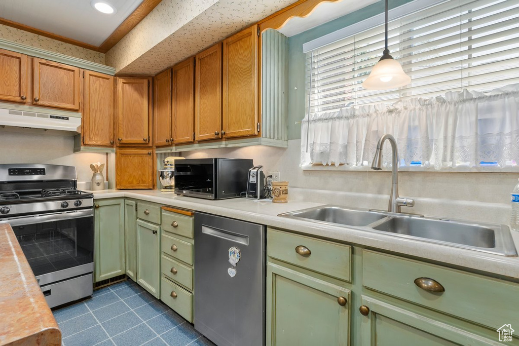 Kitchen featuring green cabinetry, appliances with stainless steel finishes, light countertops, and dark tile patterned floors