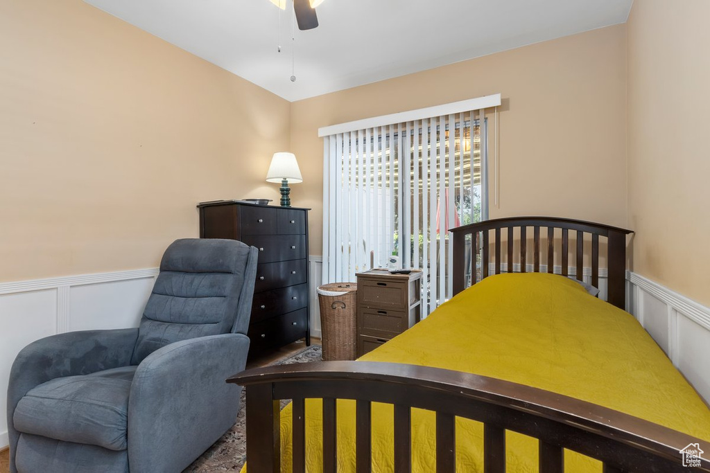 Bedroom featuring wainscoting, a decorative wall, and a ceiling fan