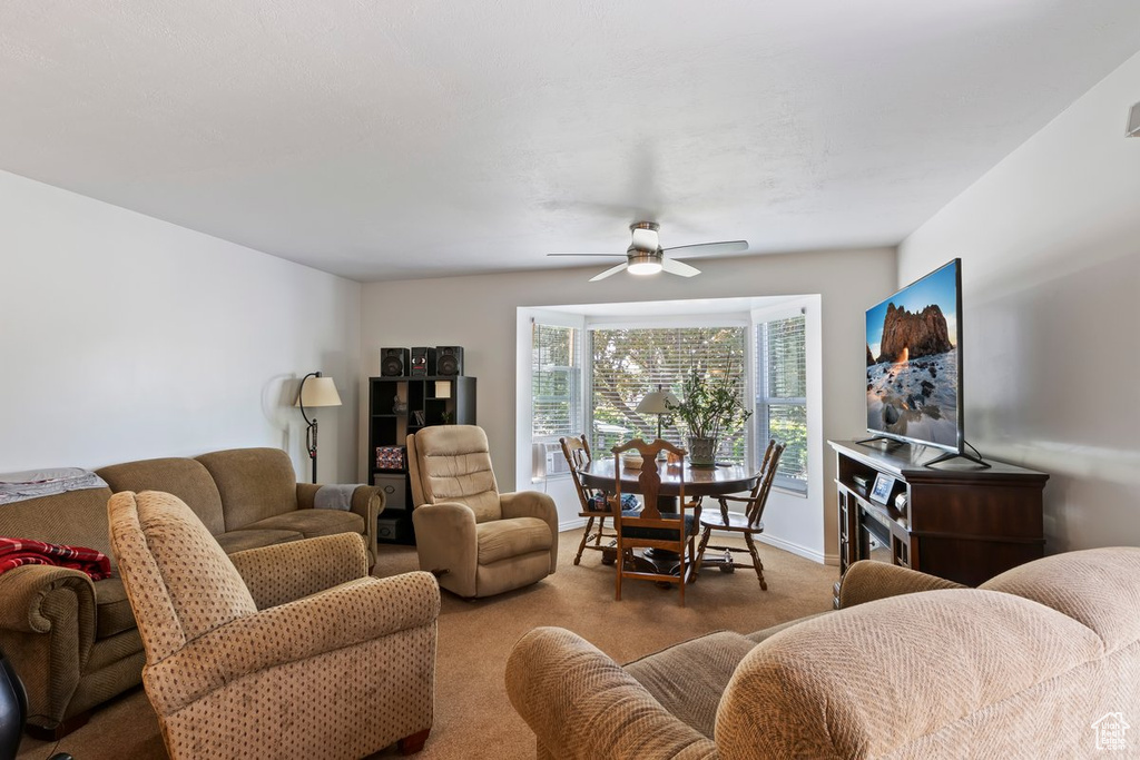 Carpeted living room with ceiling fan and baseboards