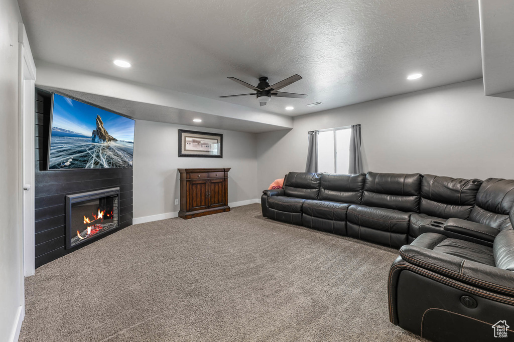 Living area featuring carpet floors, a ceiling fan, a large fireplace, recessed lighting, and a textured ceiling
